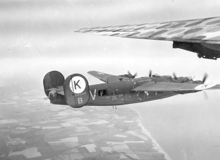 An Army photographer in First Sergeant snaps a photo of a B-24J Liberator of the 458th Bombardment Group climbing out of England and crossing the coast of the English Channel.
