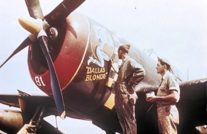 Two ground crew add the finishing touches to the nose art of a 352nd Fighter Group P-47 Thunderbolt nicknamed “Dallas Blonde”. Handwritten on slide casing: ‘P-47, 352nd F.G.’