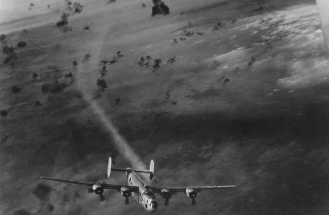 B-24 flying through thick FLAK, one engine has been hit and is smoking