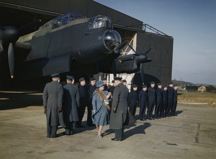 HM Queen Elizabeth inspecting flight and ground crews on a visit to Warboys, a station of No 8 Pathfinder Group. An Avro Lancaster of No 156 Squadron, Royal Air Force is seen in a T2 hangar. 10 February 1944
